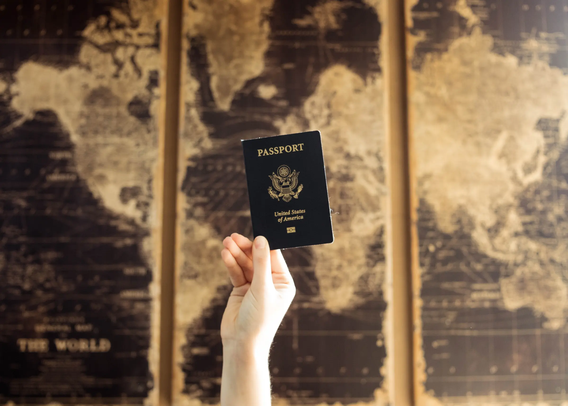 Passport held in front of a vintage world map