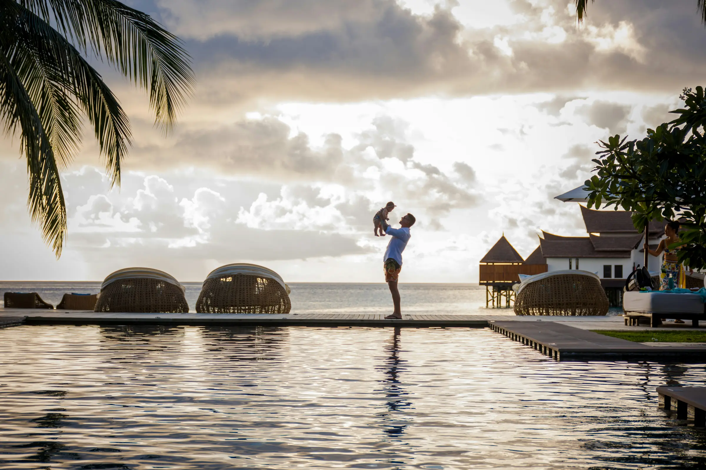 Father and child enjoying a quiet moment beside a tropical infinity pool