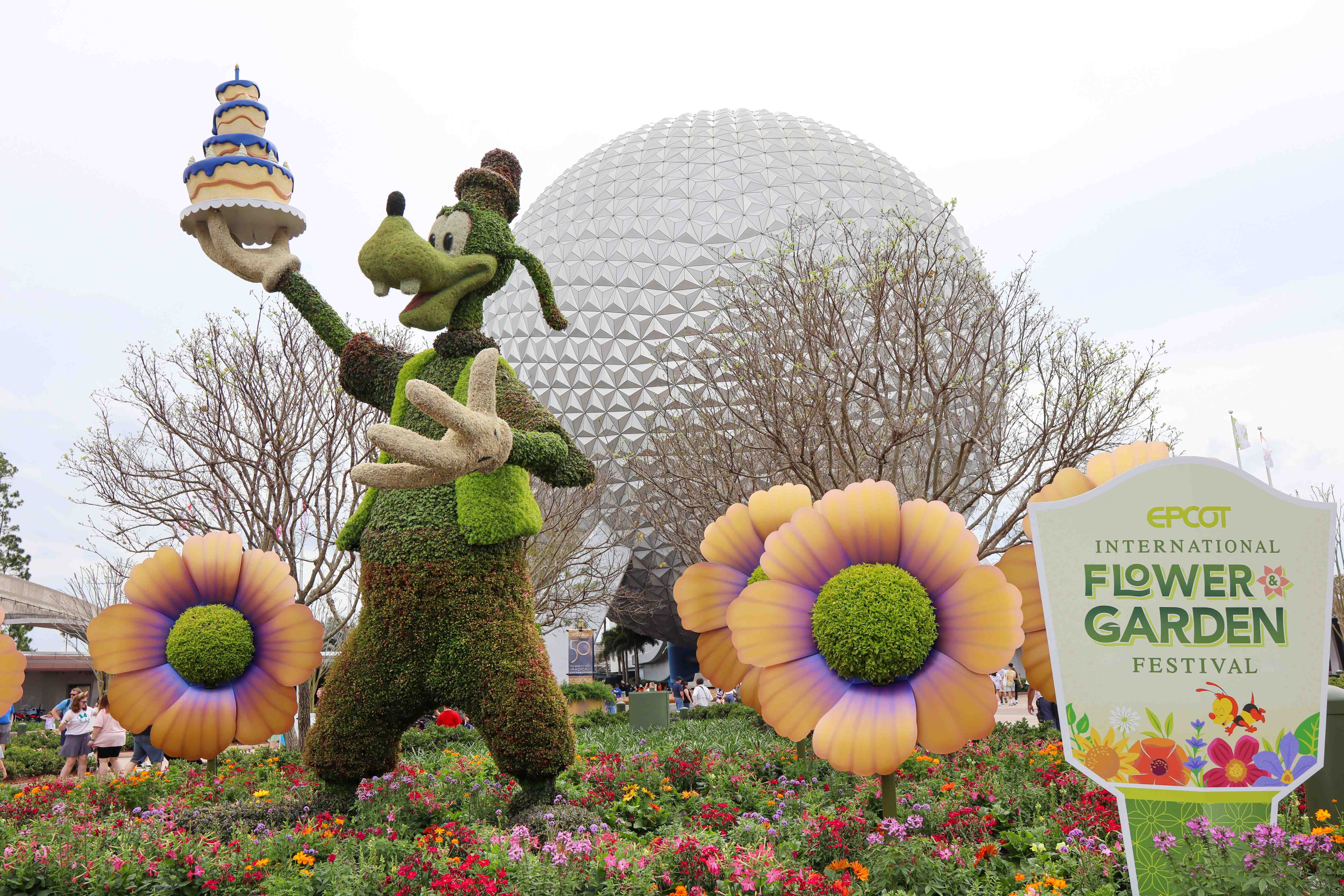 Pluto beside a colorful flower display during the EPCOT International Flower and Garden Festival