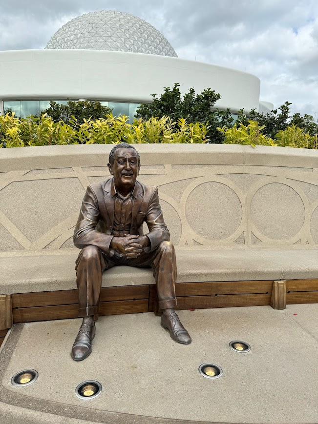 The Walt Disney statue with Spaceship Earth rising behind it at EPCOT